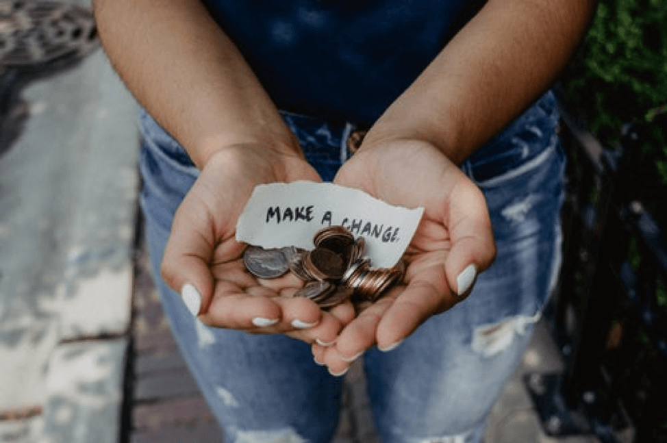 Hands holding coins with a "Make a Change" sign