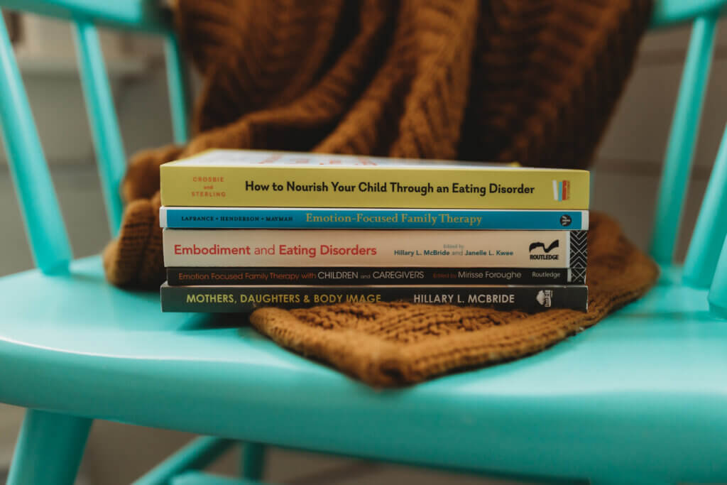 A stack of books about eating disorders in children sits on a bright blue chair