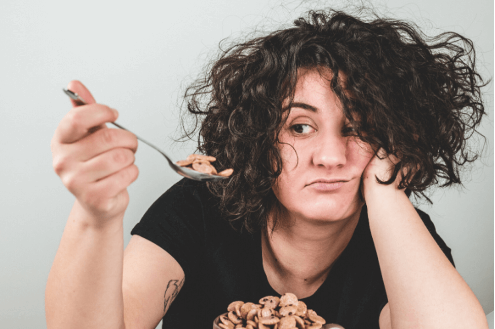 A woman reluctantly eating cereal