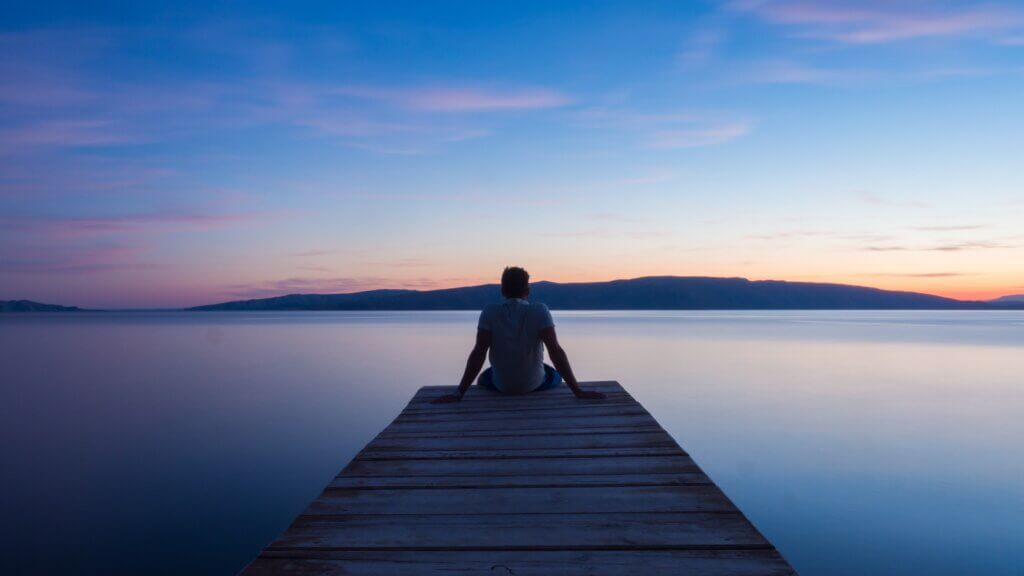 image of male sitting at the dock watching sunset