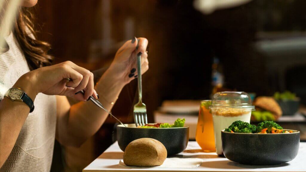 Individual eating a meal from a bowl at a table.