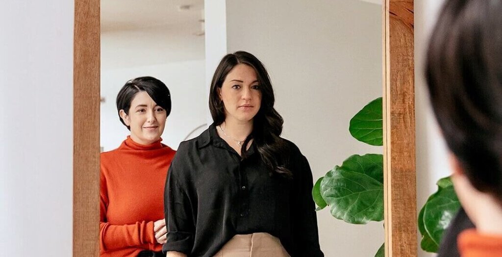 Two people looking into full length mirror