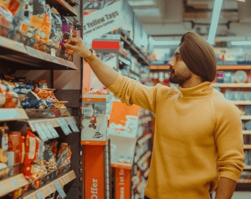 Person grabbing a food item from a shelf in a grocery store.