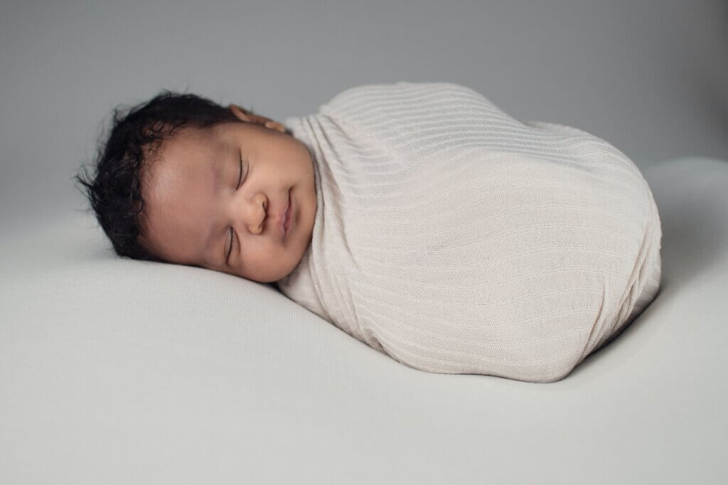 Baby wrapped in a blanket with a white background