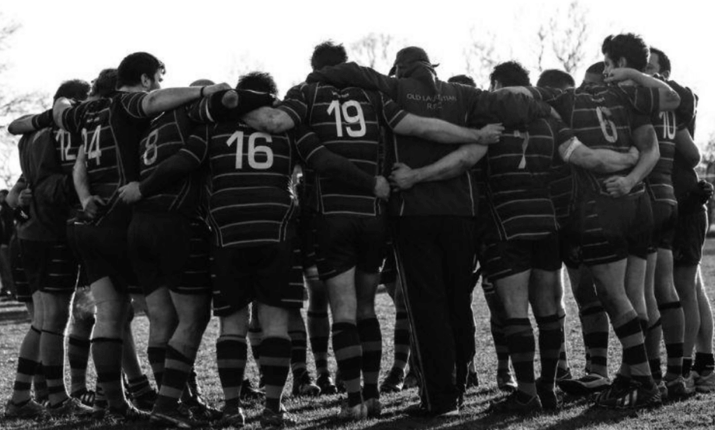 A group of male soccer players in a huddle; one of the males has an eating disorder. 