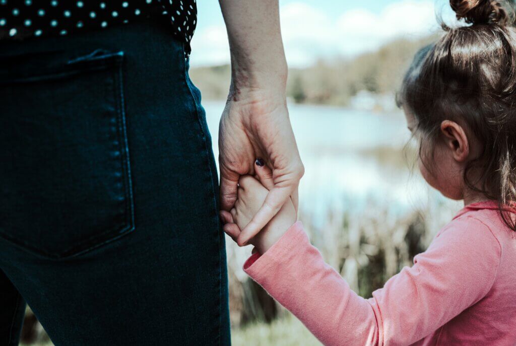 Image of caregiver and child holding hands.