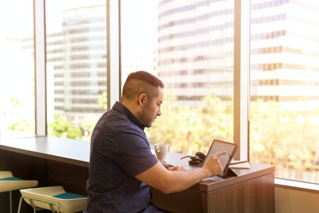 Person sitting at a desk on their iPad in front of a window