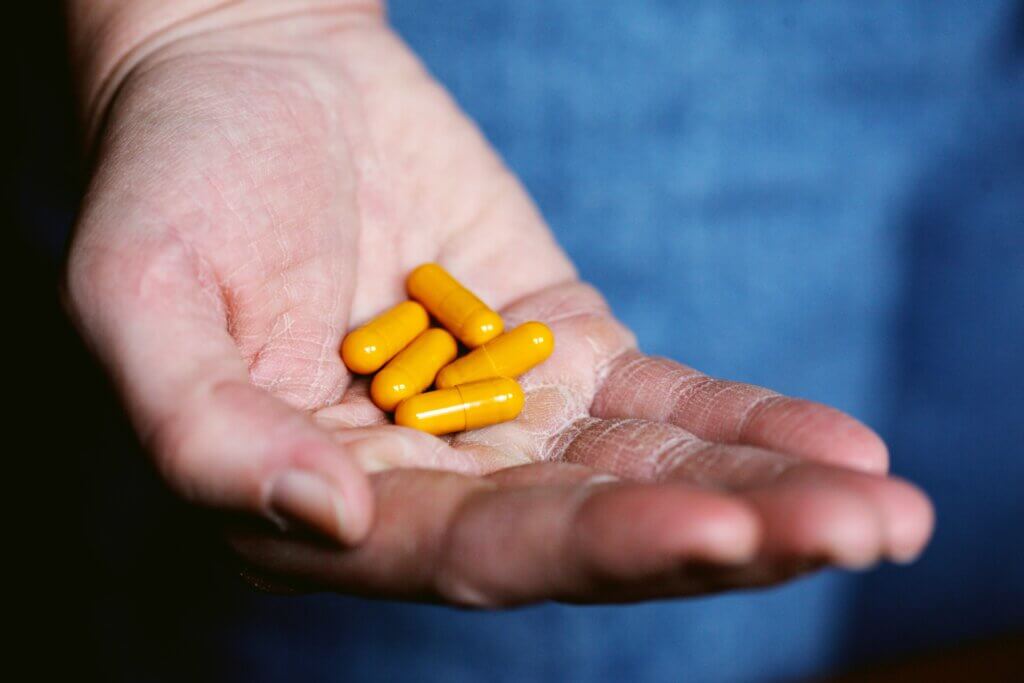 Person holding a few yellow pill capsules