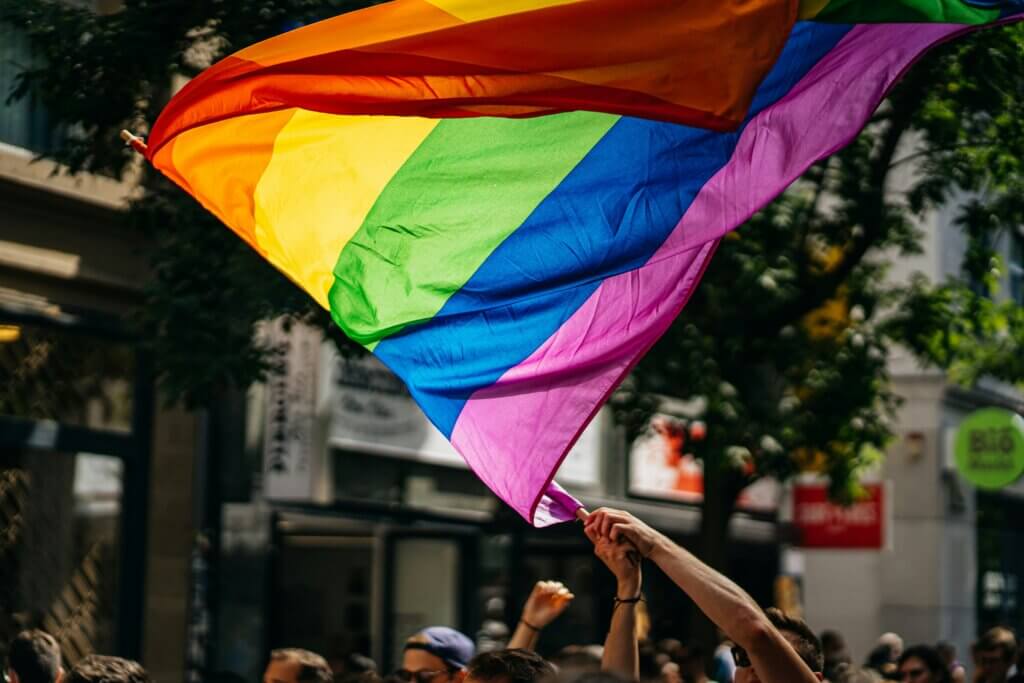Someone flying the pride flag at a pride parade.