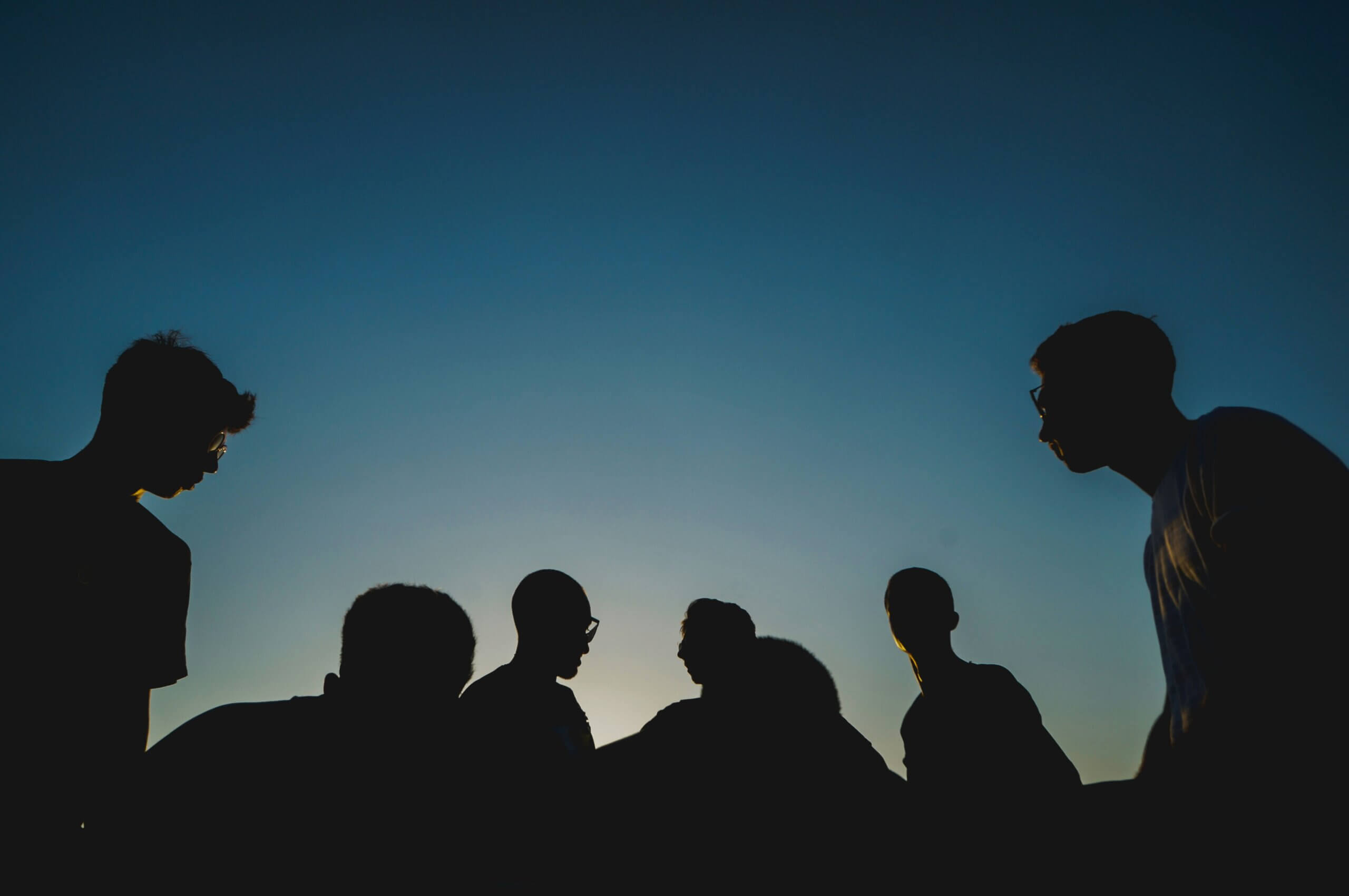 Group of male silhouettes against a sunset