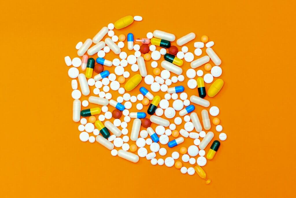 Different shaped and coloured pills on an orange background