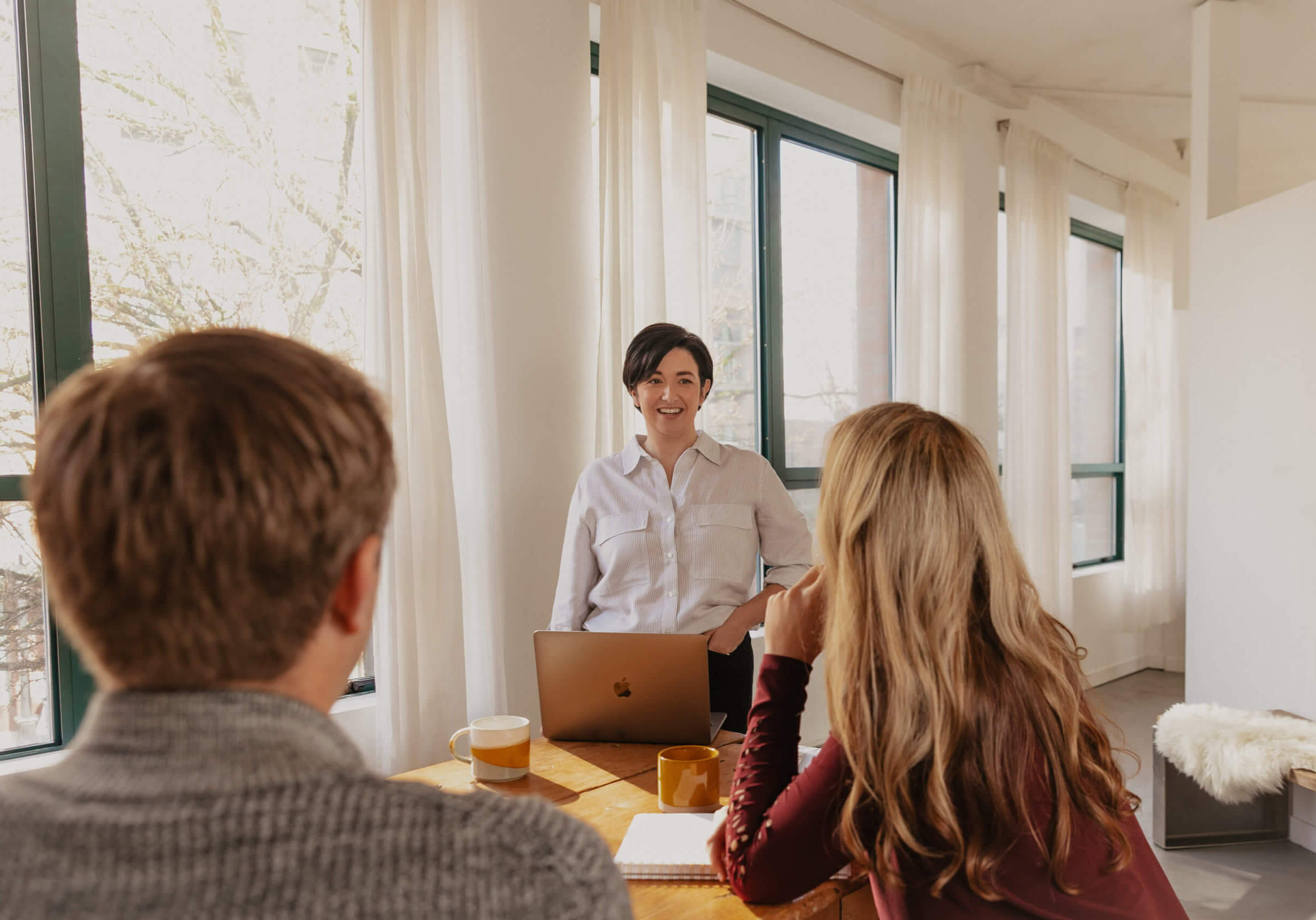 Jillian standing and teaching two others at a table.