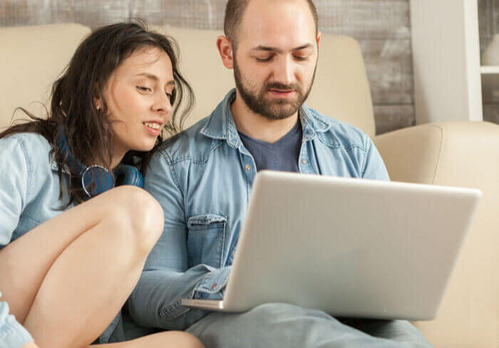 A teen looking at a laptop with her father