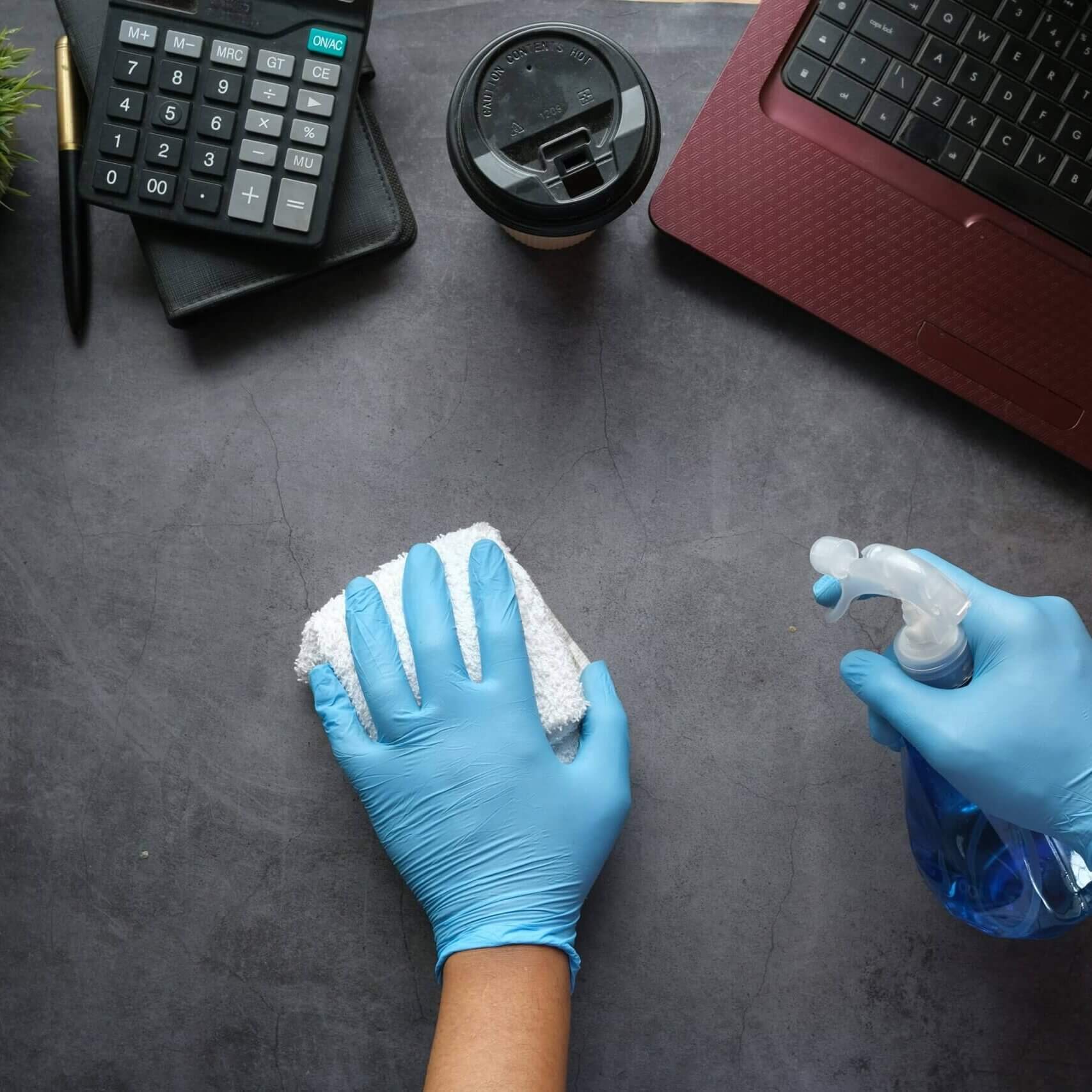 Someone cleaning their desk wearing gloves