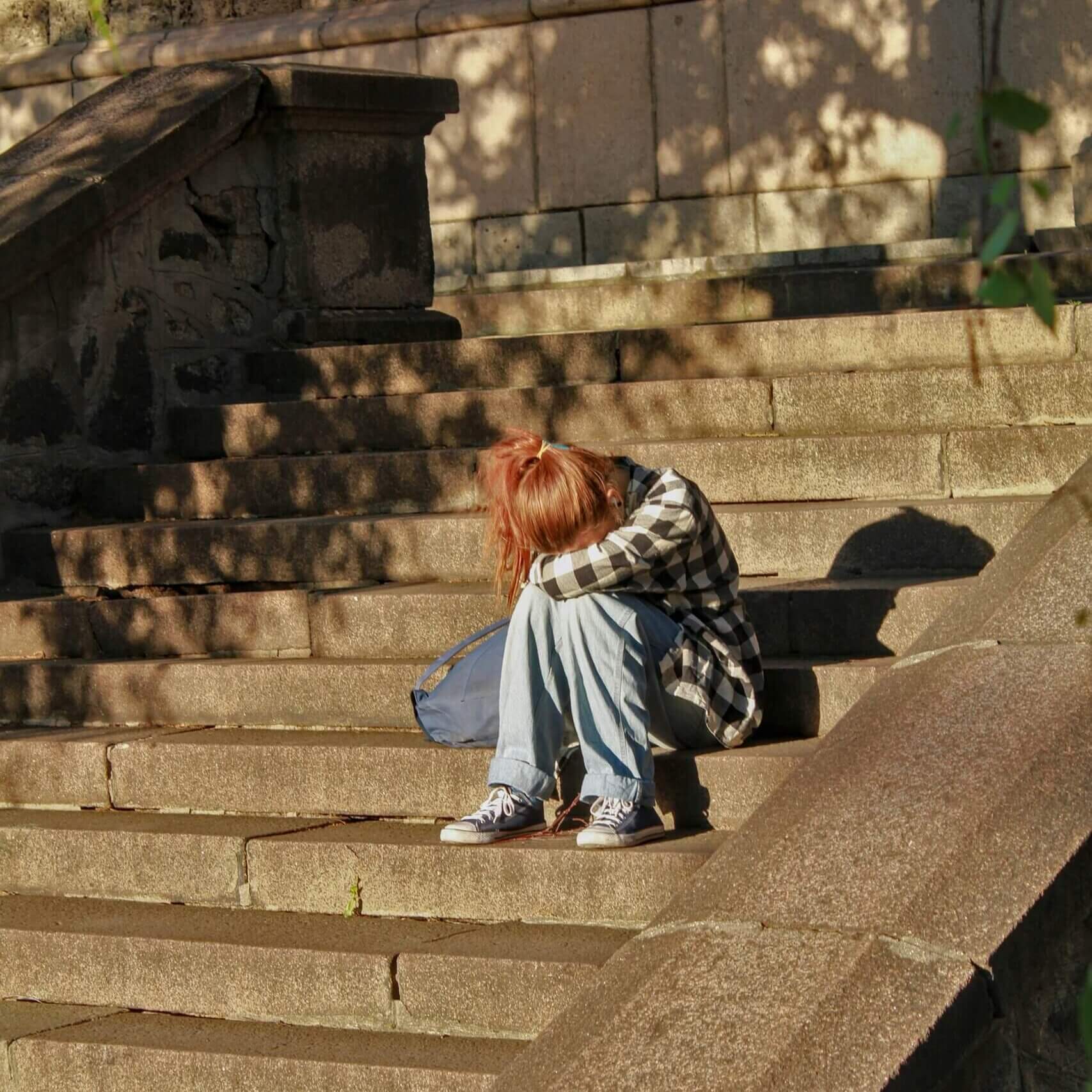Child sitting on concrete steps along with head in hands